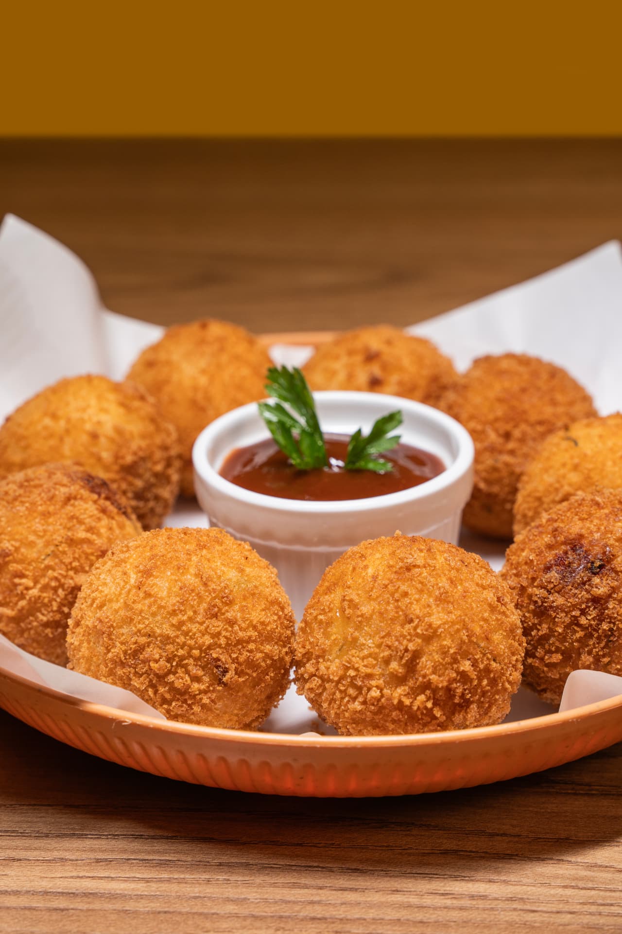 Bolinhos dourados de mandioca com carne seca servidos com molho